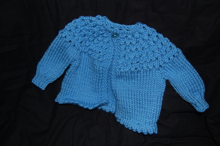 an infant sweater lying on a black background
