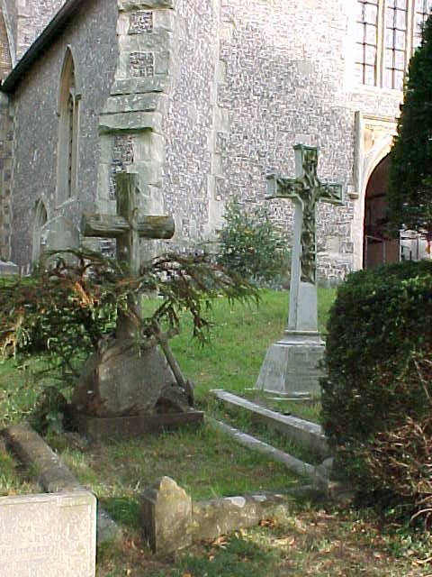 a cemetery with a stone cross and tree in front
