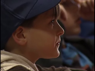 a boy in a cap smiles as he sits next to another man