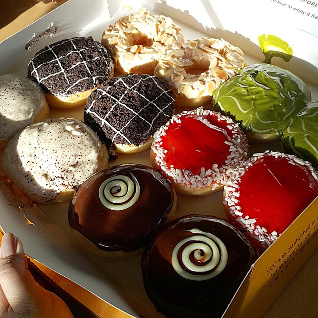 a box of donuts with various toppings is pictured