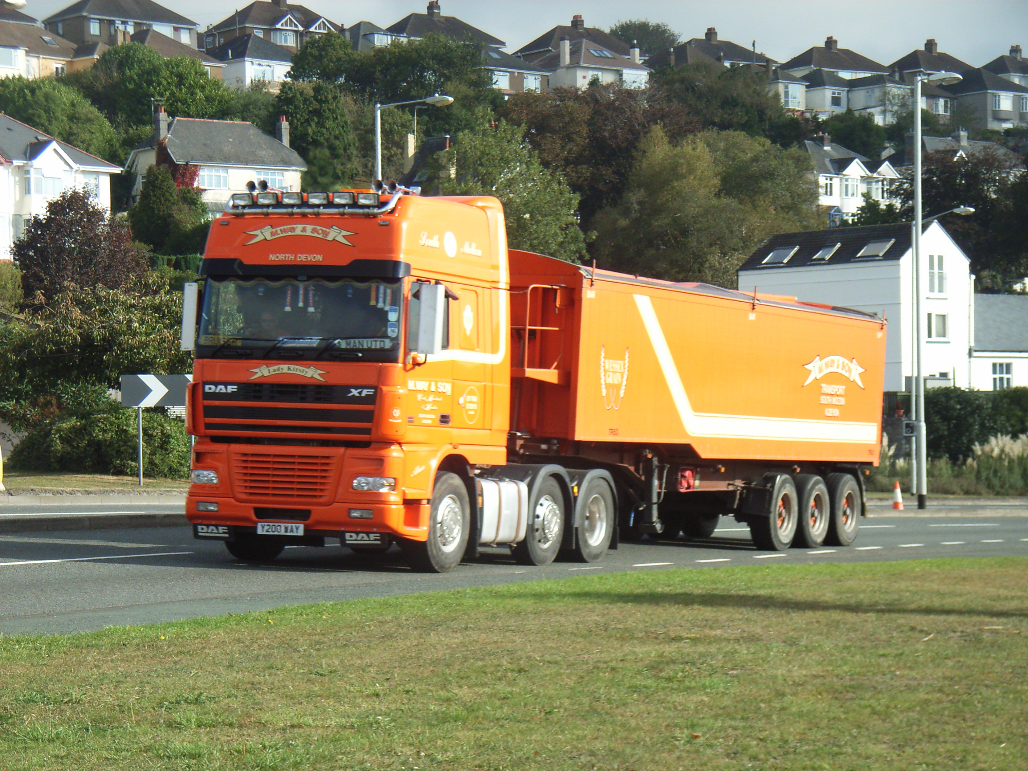 an orange and yellow semi truck traveling down a road