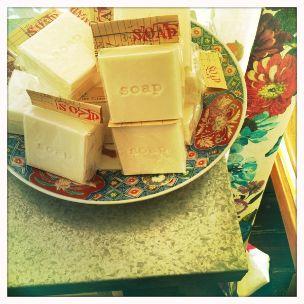 several soaps on a plate sitting next to flowers