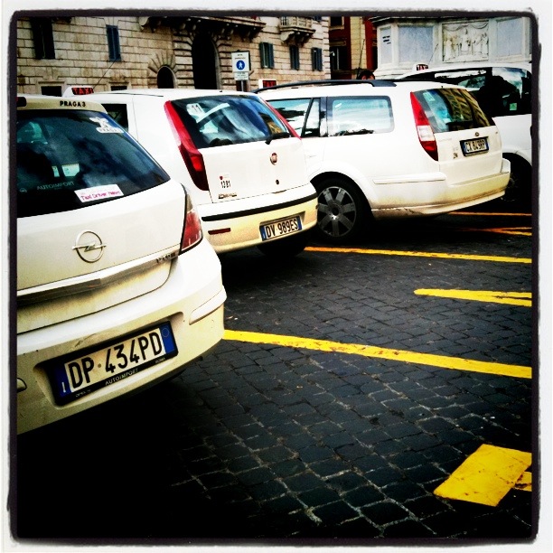 a group of white vans parked in parking spaces next to buildings