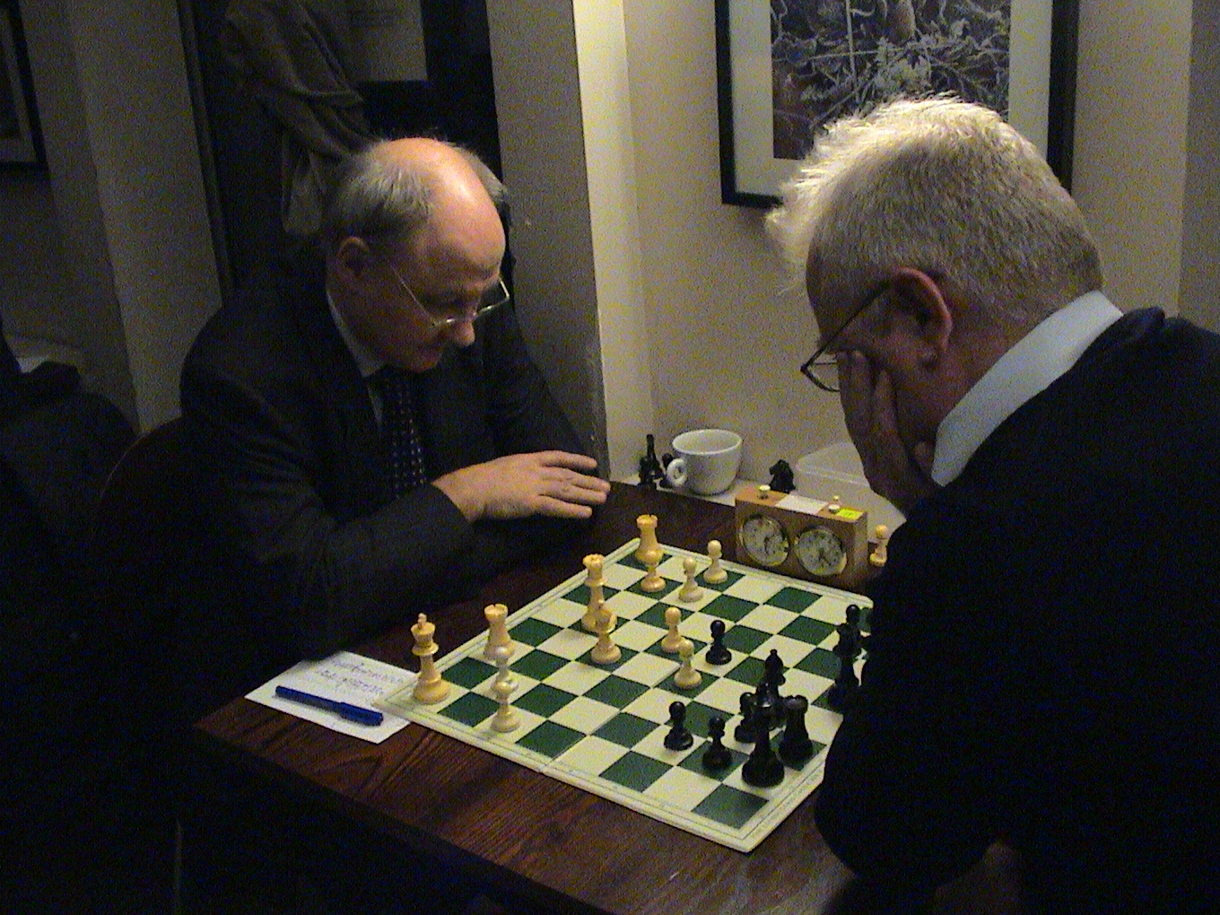 two men play a game of chess in front of their friends