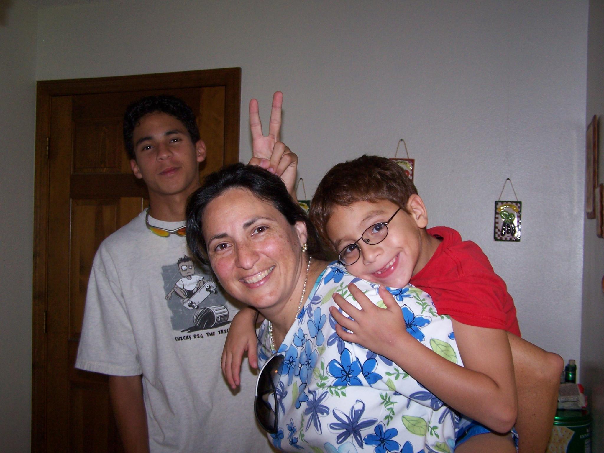 a woman standing next to two boys wearing glasses