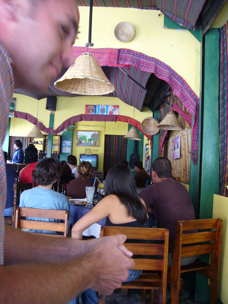 people sitting in a restaurant with a man holding a cellphone