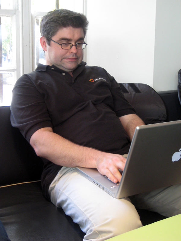man with glasses uses his laptop on a sofa