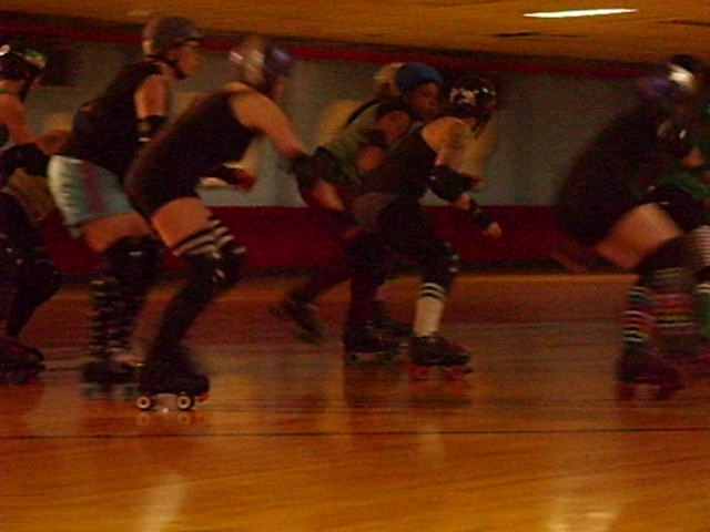 several people are rollerskarting on a wooden floor