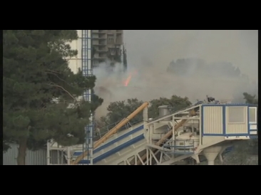 smoke pouring from large stacks of concrete near construction site