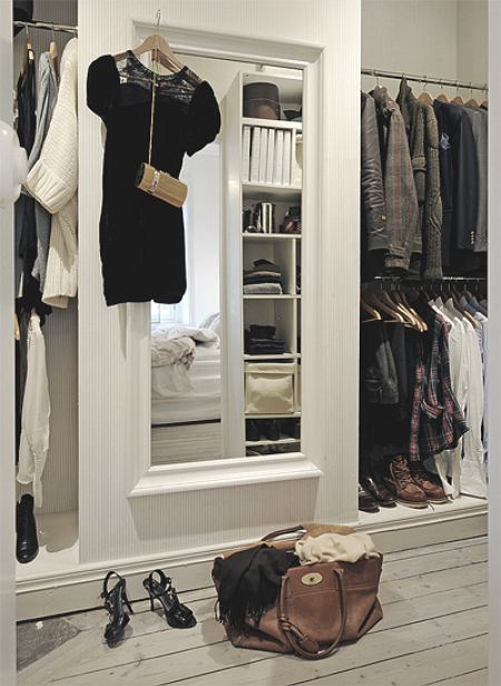 a walk - in closet with a large mirror, a handbag and two pairs of shoes