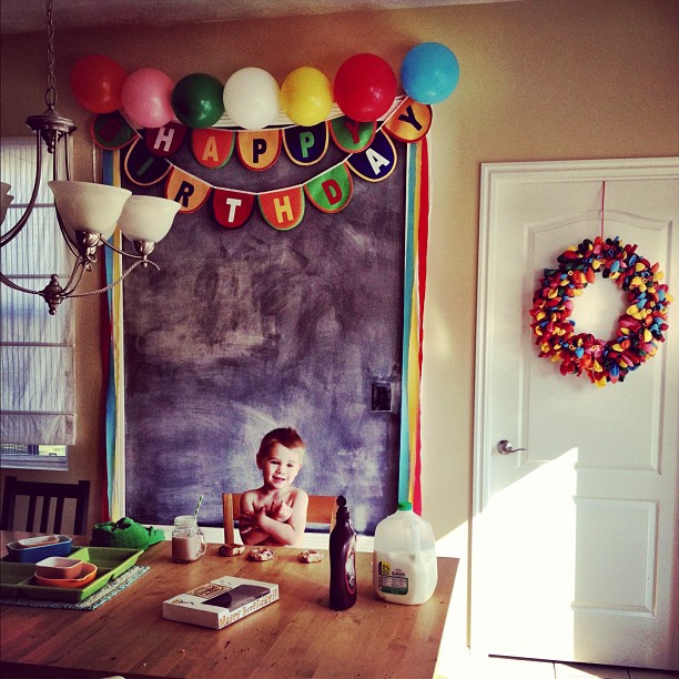 the baby is sitting at the table in front of balloons