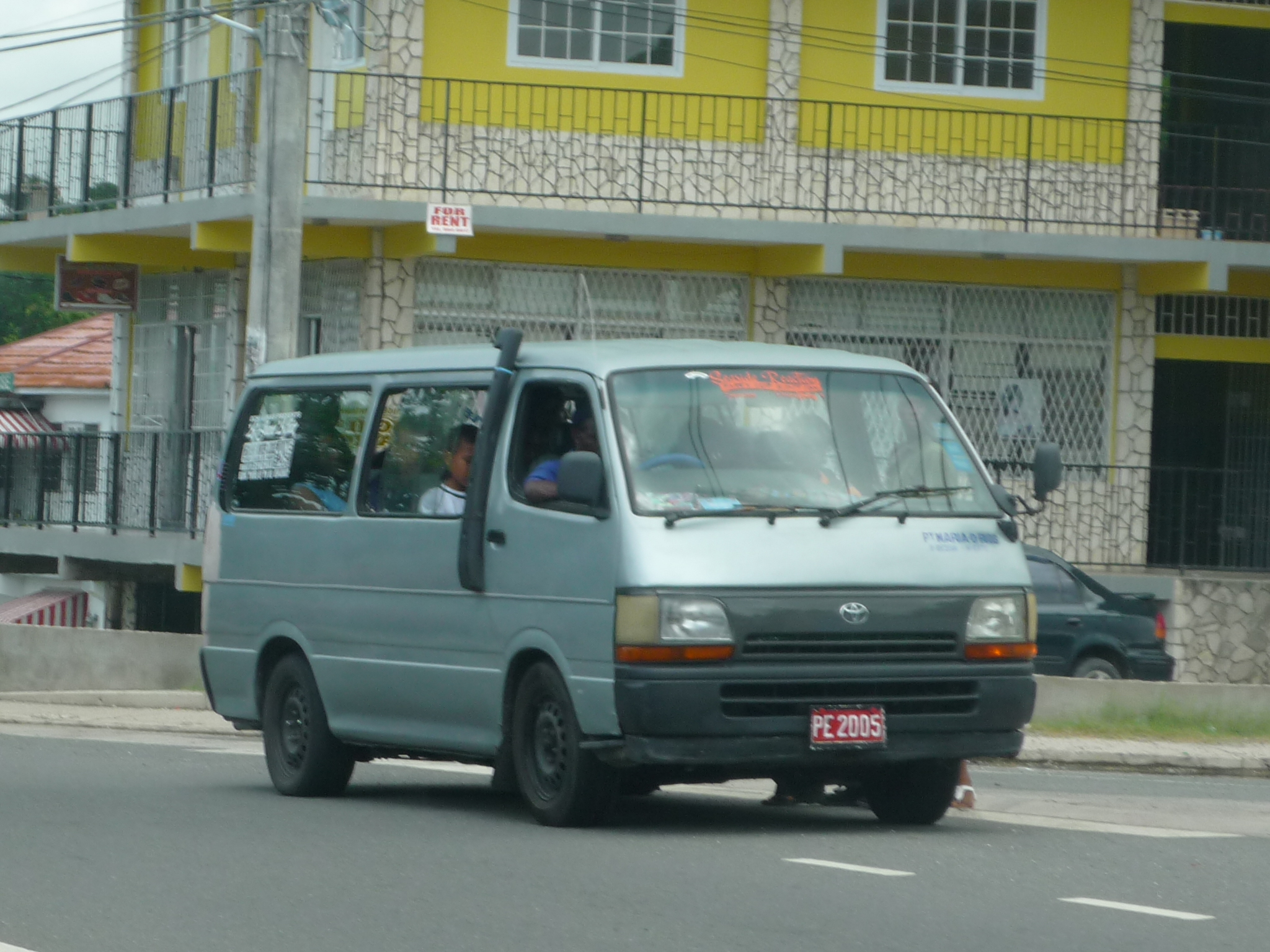 a small van parked by the curb with people looking out the window