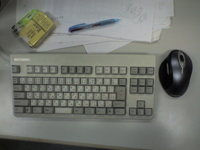 there is a keyboard, a mouse, and some papers on this desk