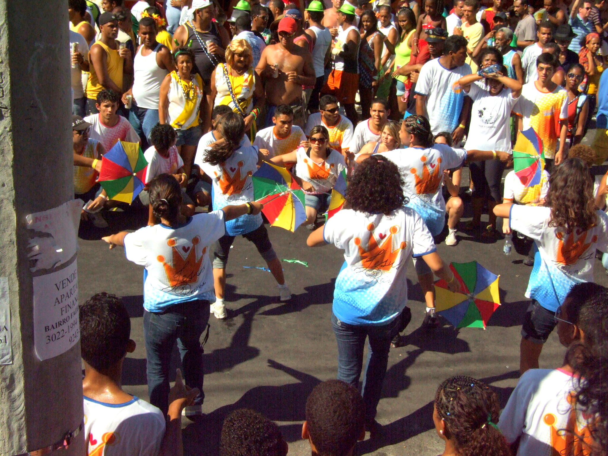 people standing on a sidewalk holding kites