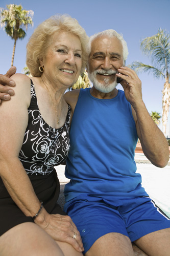 an elderly couple poses on a bench for a po