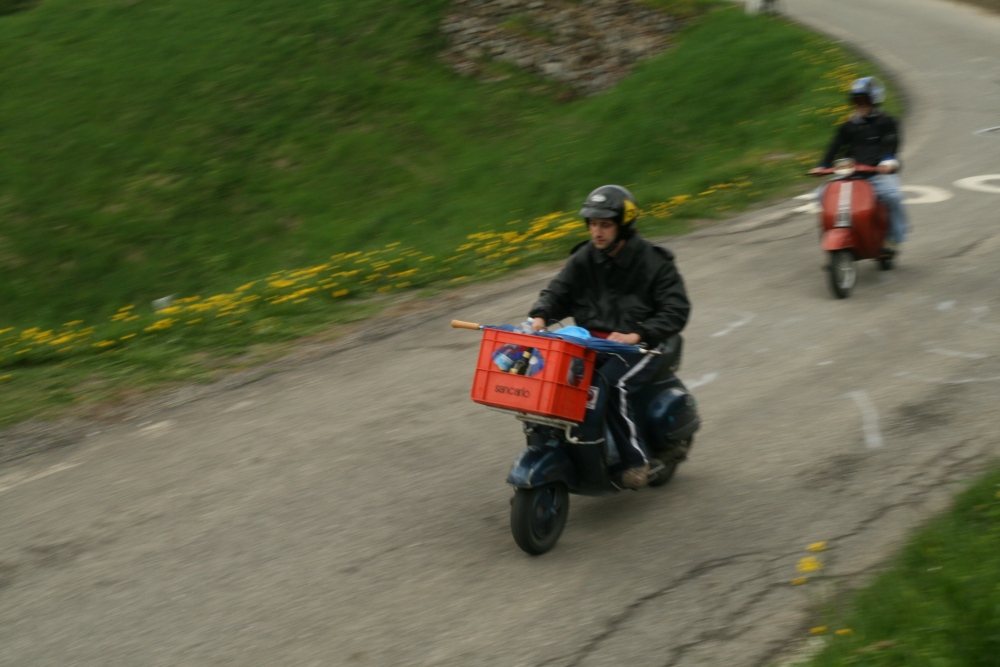 some people riding motorcycles on a narrow road