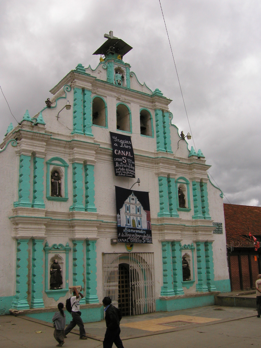 a church in the street with blue windows and people walking by