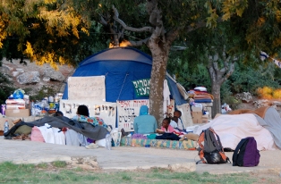 people are outside camping tents under trees in the desert