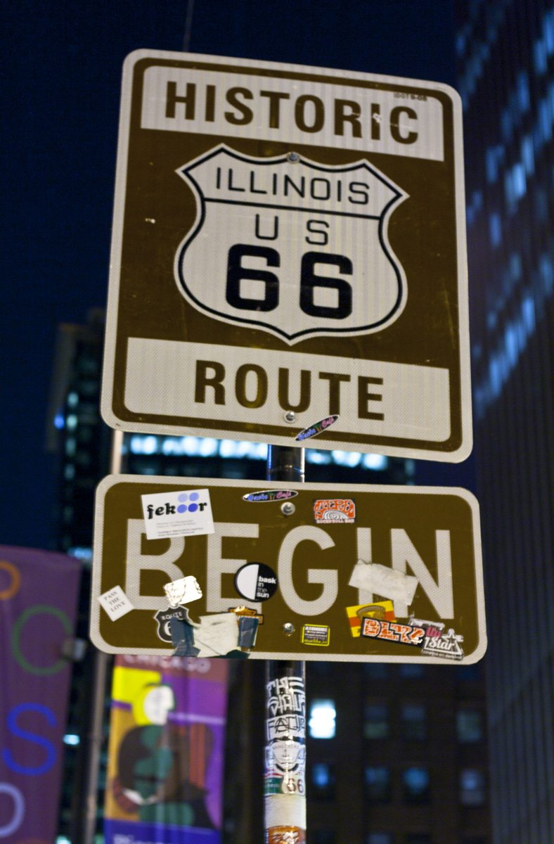 a close up of a street sign with other signs and buildings in the background