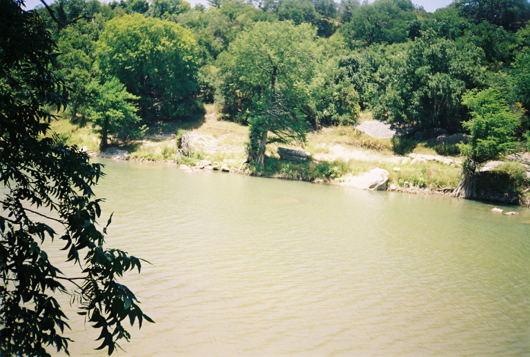 an open river surrounded by green forest