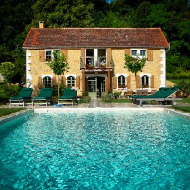 a large house with pool and outdoor lounge chairs