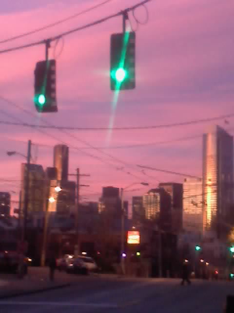 a couple of green stop lights and buildings at dusk