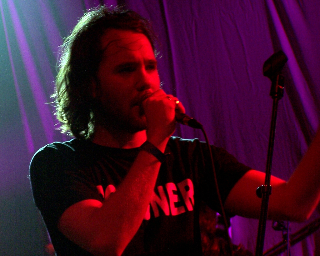 a man with long hair singing into a microphone