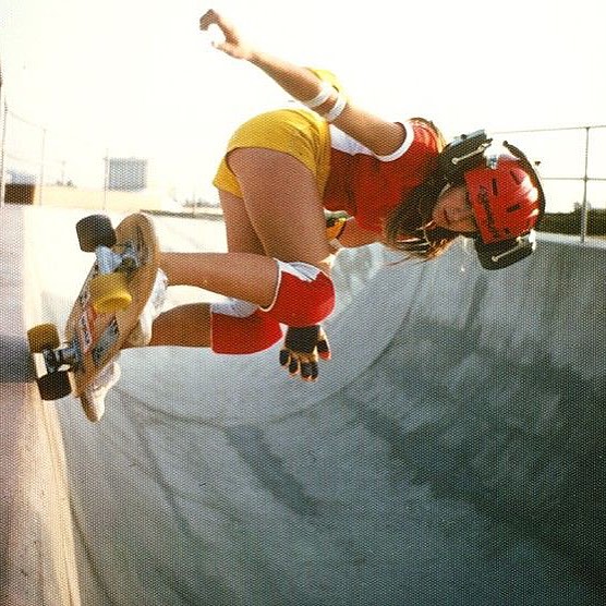 a woman skateboards at the top of a bowl