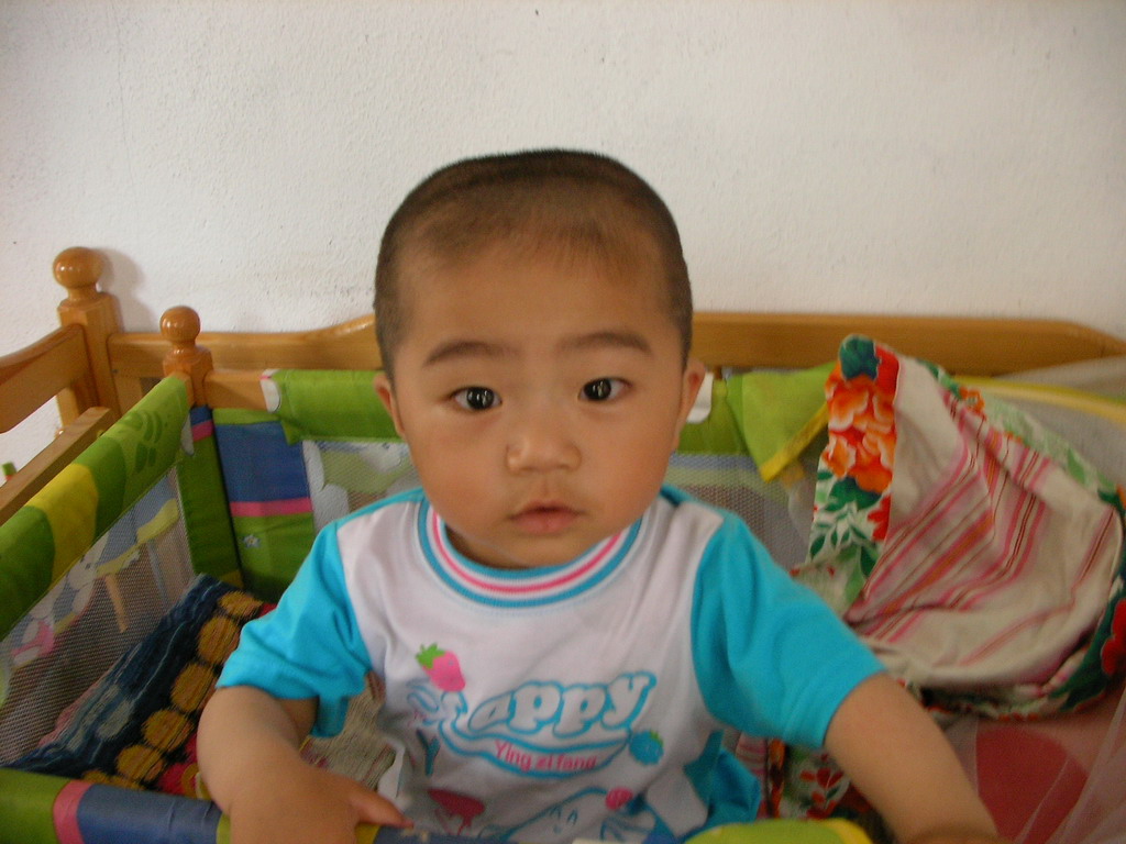 a small baby sits on a crib near a wall