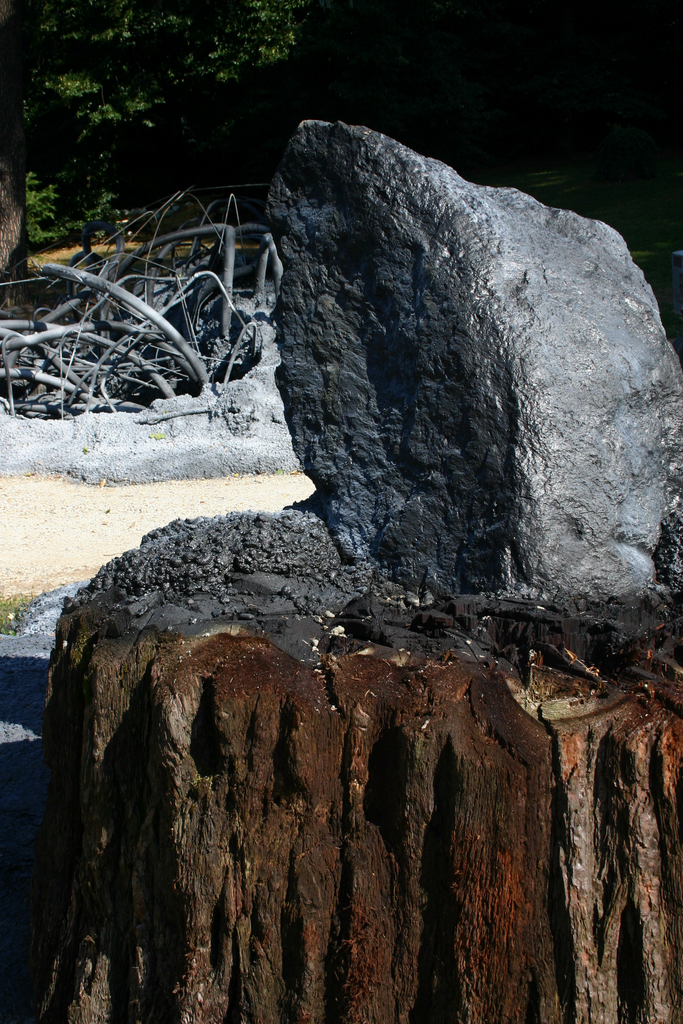 large rock sitting on top of a stump in a park