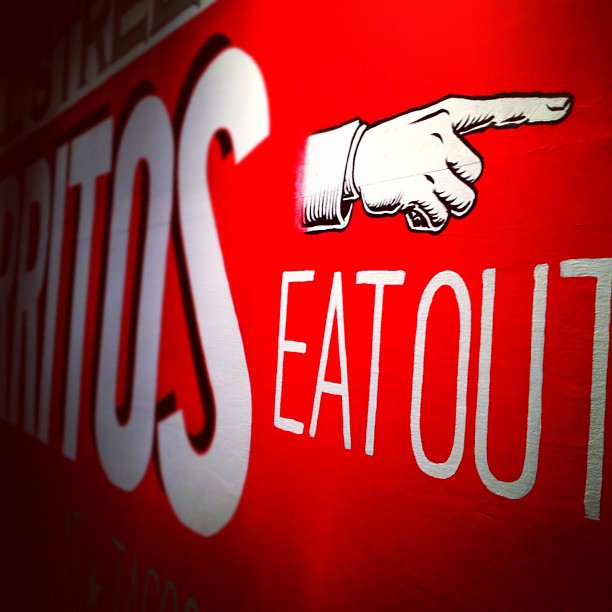 red sign with hand pointing toward eat out sign