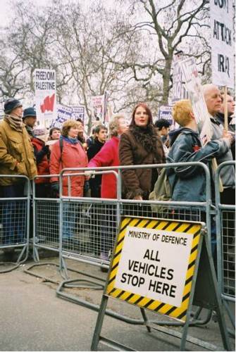 people standing in line behind metal barricades with signs