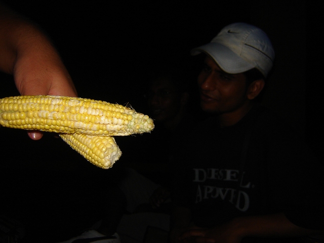 a man holding a corn on the cob and another person
