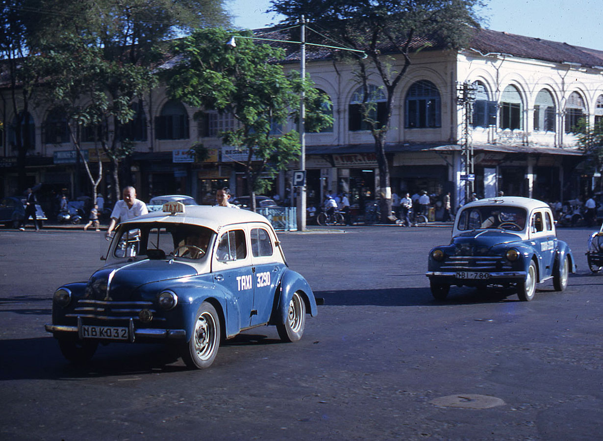 three old cars are riding down the street