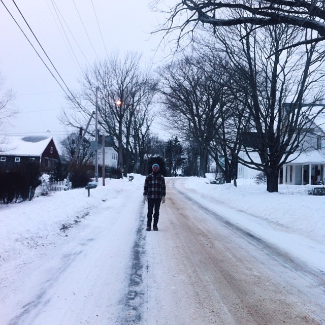 a person walking down a snowy street, holding an umbrella
