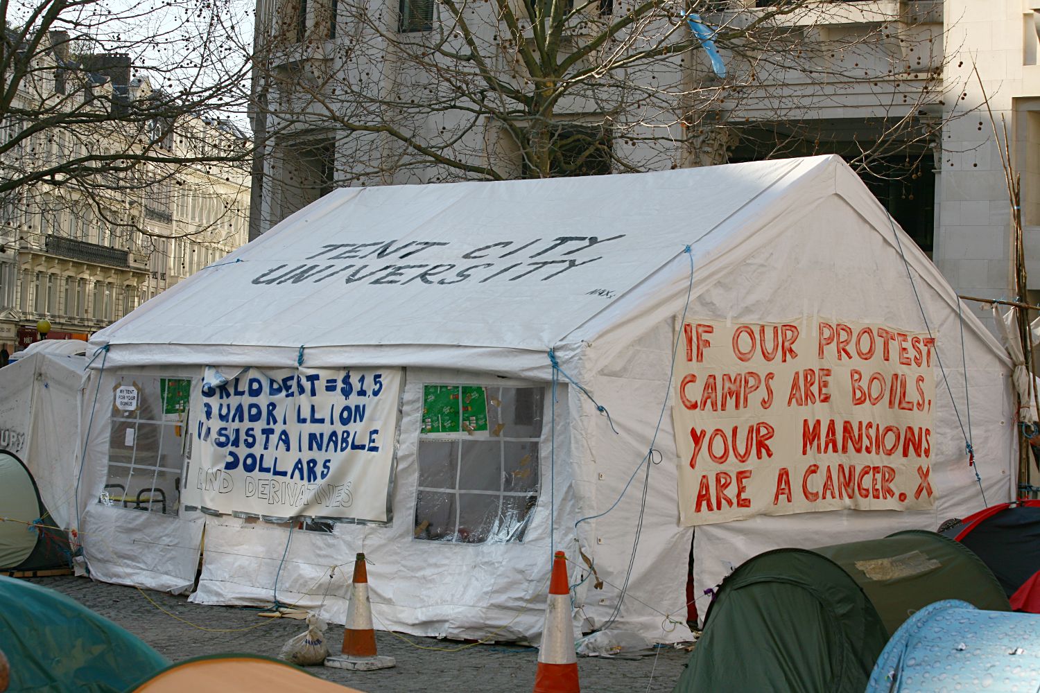 several tents with signs set up against the side of a building