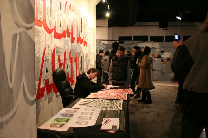 a group of people looking at posters on the wall