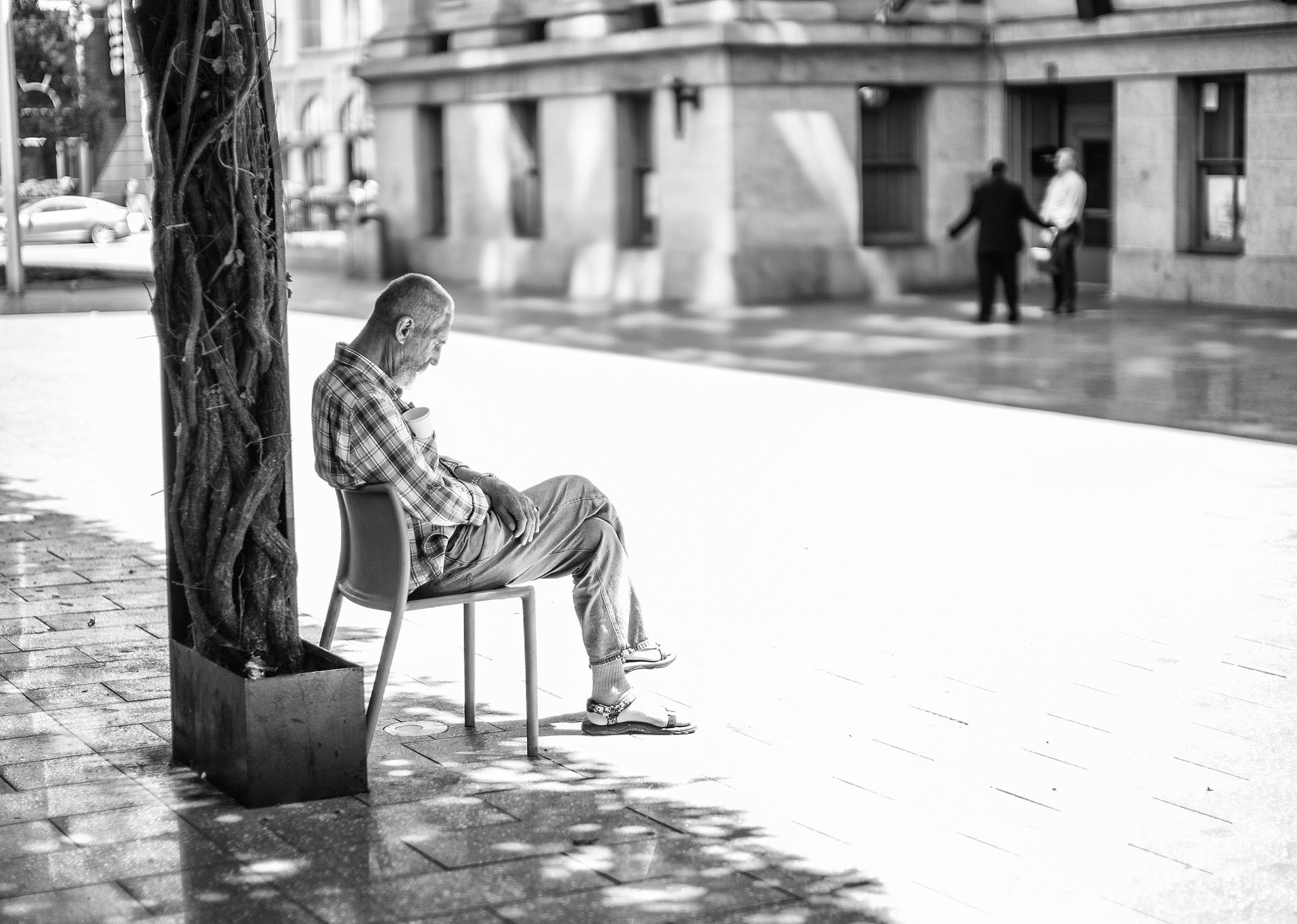 man in plaid shirt sitting on park bench with cellphone