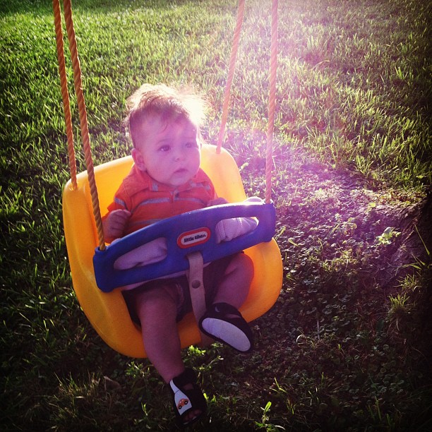 a baby sitting in the middle of a swing