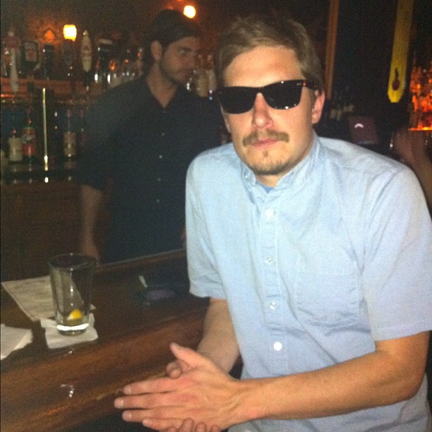 a man in glasses is sitting at a bar