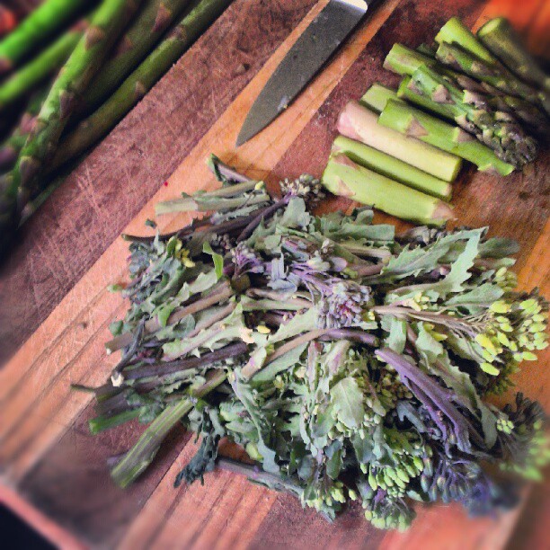 several bunches of green vegetables on a  board