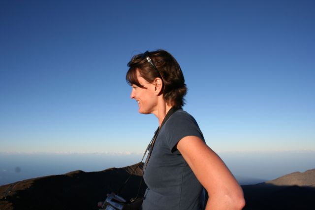 a woman is standing at the top of a mountain