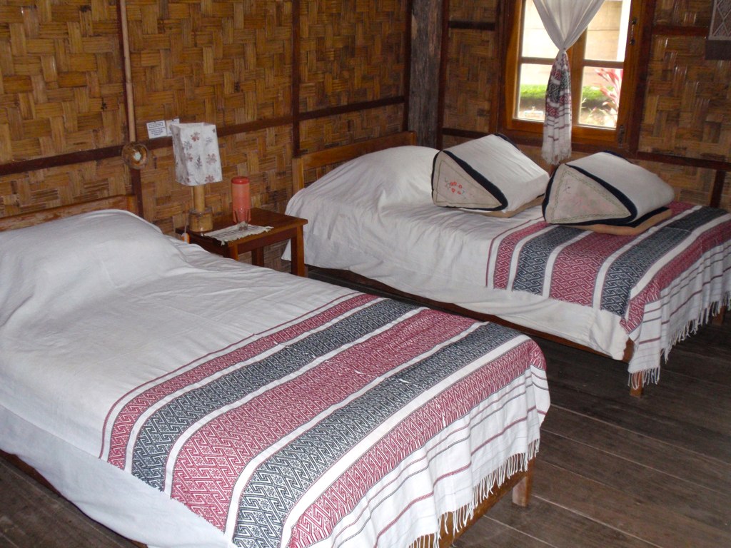 twin beds are in a rustic lodge with wood floors