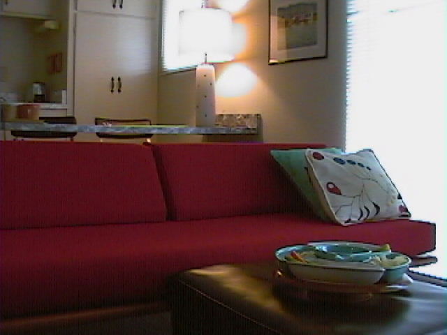 a red couch in the living room with pillows and plate on it
