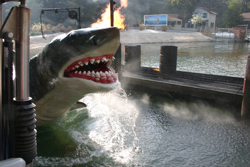 a big shark statue in the water with a fire coming out of its mouth