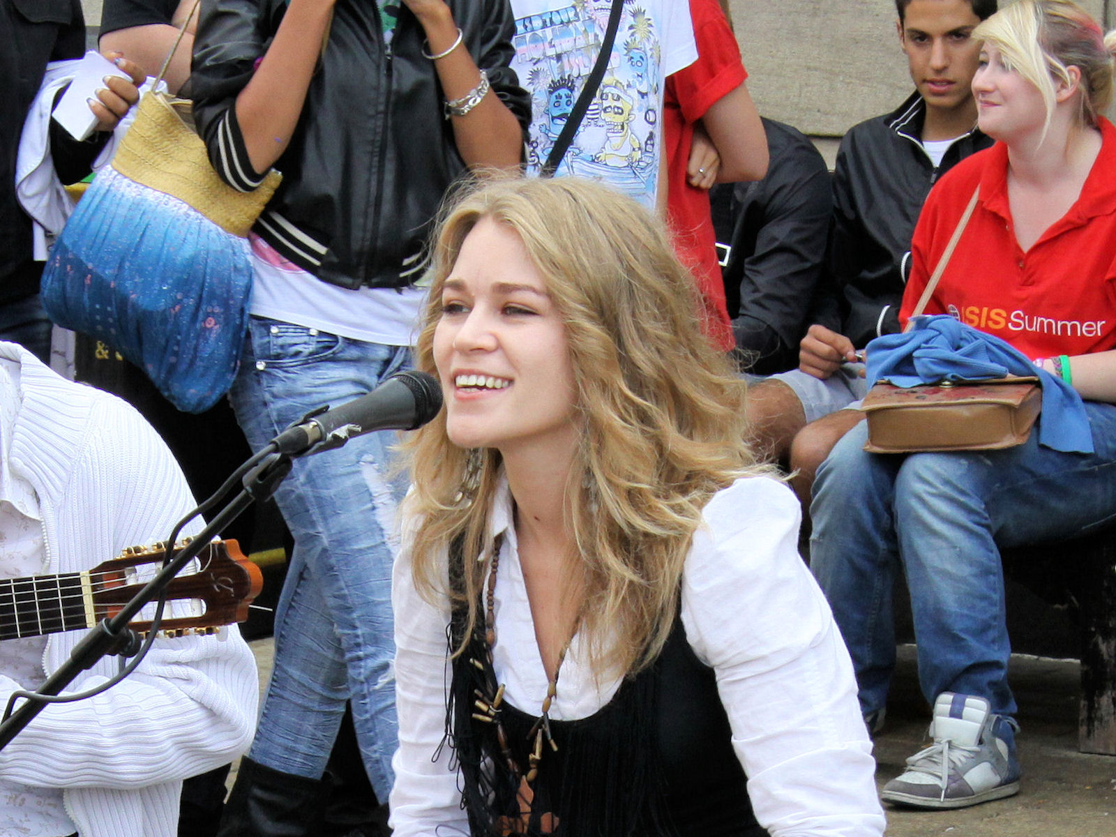 a woman with long blonde hair smiling in front of a microphone