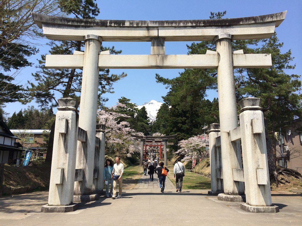 people are walking underneath a stone arch in a garden