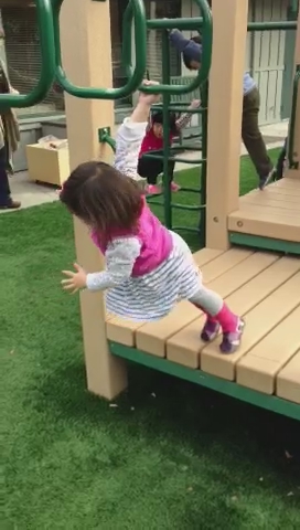a girl swinging on a wooden slide on grass