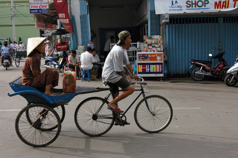 man riding bike holding a basket on it, and another person riding a motorcycle
