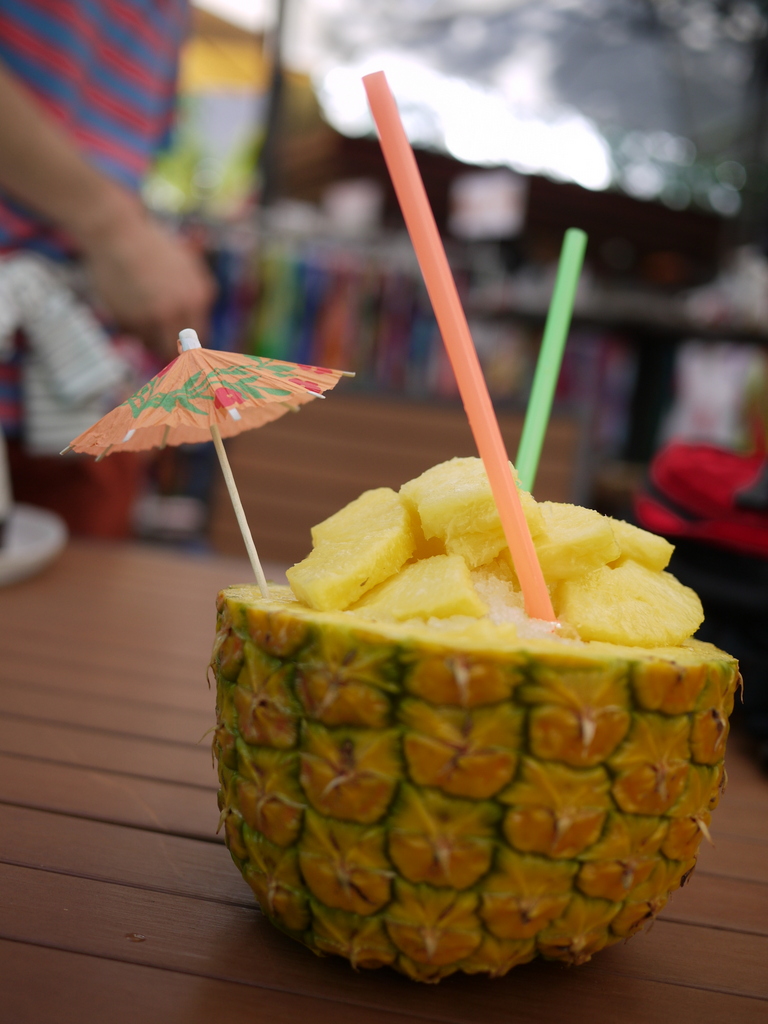 a small pineapple drink in a glass with straws and a umbrella